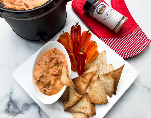 a bowl of a cheesy dip served with sliced bell peppers and pita chips, photo credit MyCuratedTastes