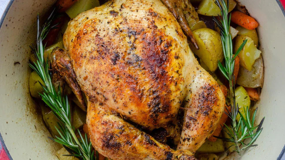 roasted chicken in a ditch oven with carrot, onion, potato and rosemary.