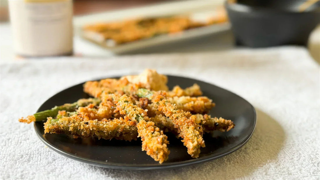 Breaded and crisp asparagus on a black plate