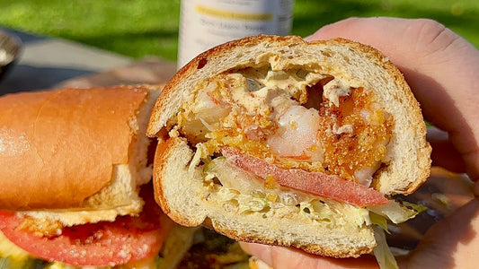 Shrimp Po Boy cut in half to show the inside of shrimp, lettuce, tomato and sauce. 