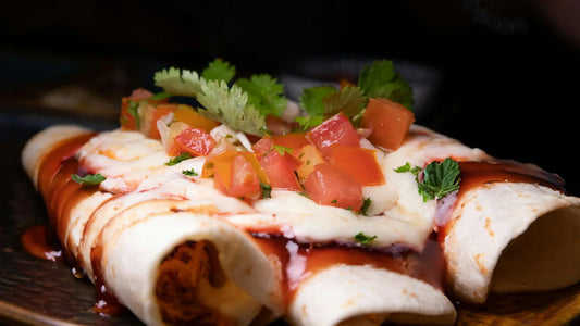 Enchiladas with red and white sauce with fresh tomato and cilantro on top. 