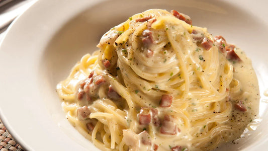 Creamy pasta in a dish with bacon and herbs