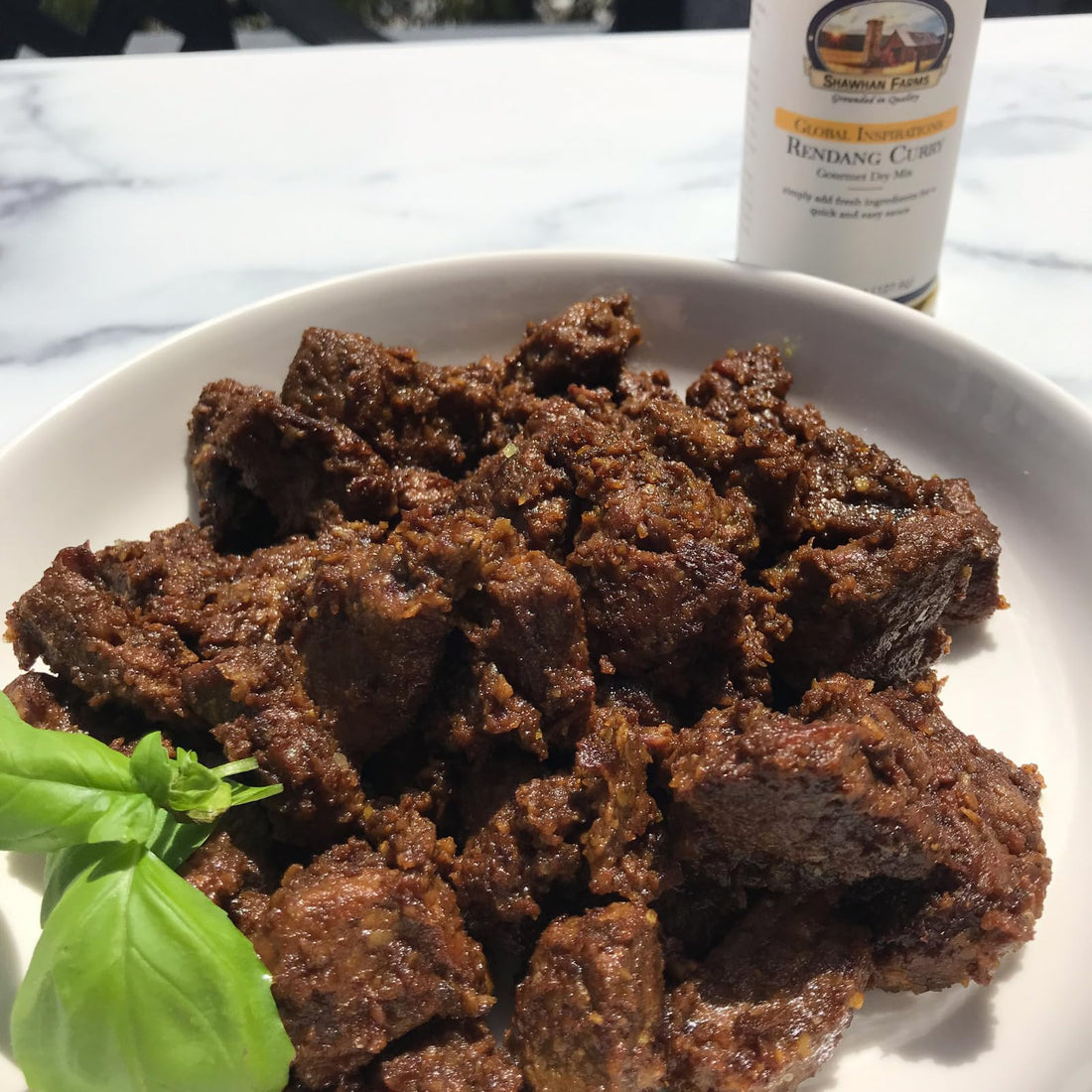 browned beef chunks on a white plate on a marble countertop