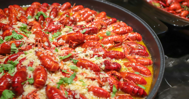 Crawfish in a sauce pan, cooked to a bright red shell in butter, garlic, herbs, and seasoning. 
