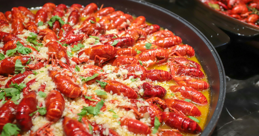 Crawfish in a sauce pan, cooked to a bright red shell in butter, garlic, herbs, and seasoning. 