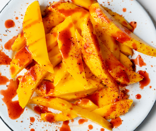 Chamoy and Tajin spread over sliced mango.