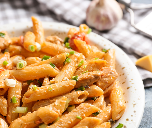 Pasta in a bowl with chicken, green onion & spices