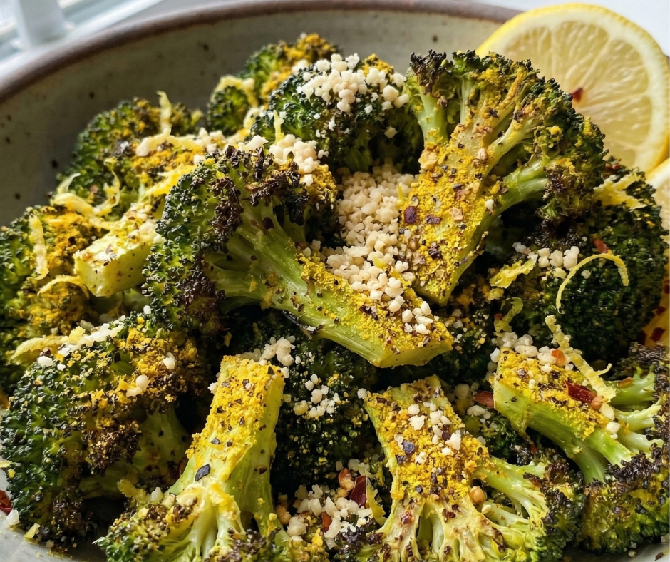 Broccoli in a bowl with lemon pepper parm seasoning on it and lemon slices.