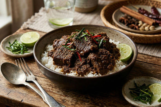 Beef in brown sauce on a bed of rice with some herbs and spices on top. 