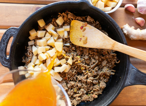 taco meat in a skillet with garlic, onion and other veggies.