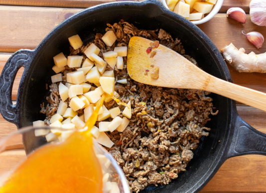 taco meat in a skillet with garlic, onion and other veggies.