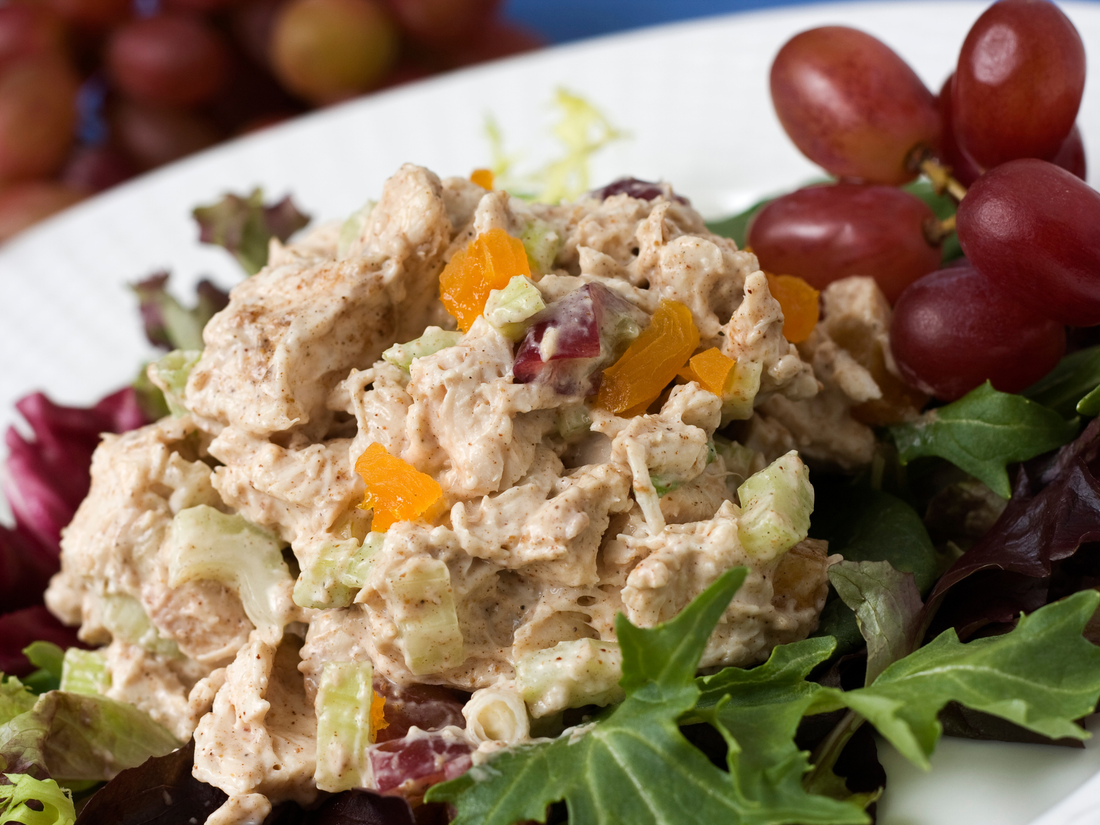 Chicken salad on lettuce next to a bunch of grapes