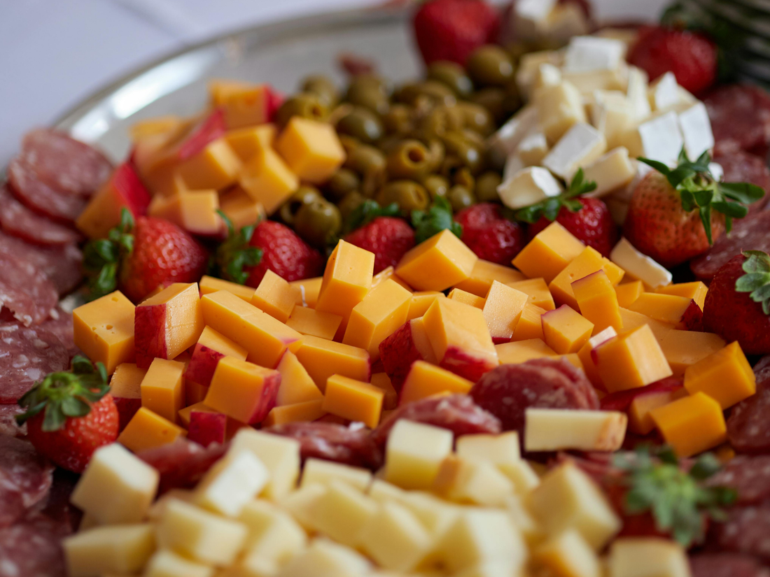 diced apple, cheese, strawberry, salami, olives and more on a plate for snacking