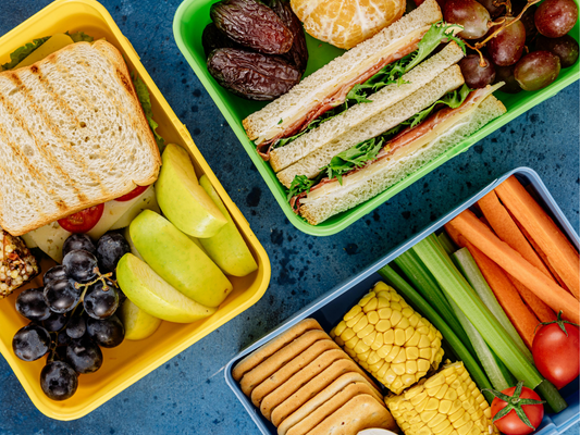 Lunchboxes with various fruits, veggies and sandwiches
