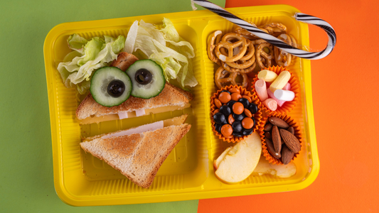 Sliced sandwich with cucumber & olive as eyes. Pretzels, candy, apple slices on the side. 