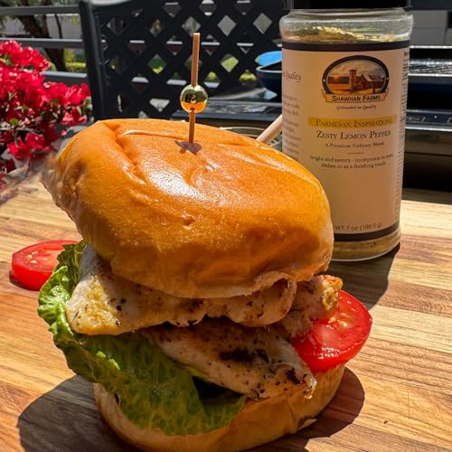 Chicken Sandwich with lettuce, tomato, and a wood skewer through the top middle. On a wooden table with a bottle of Shawhan Farms Zesty Lemon Pepper. 