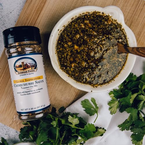 Chiumichurri sauce in a bowl with a bottle of chimichurri sauce starter next to it with fresh herbs ontop a cutting board.